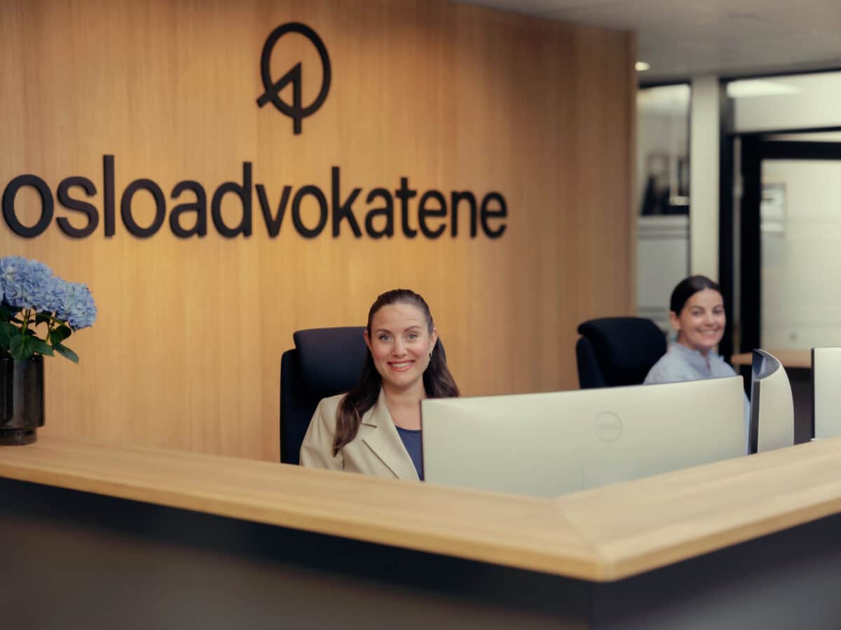 To resepsjonister smiler til kamera ved resepsjonsdisken