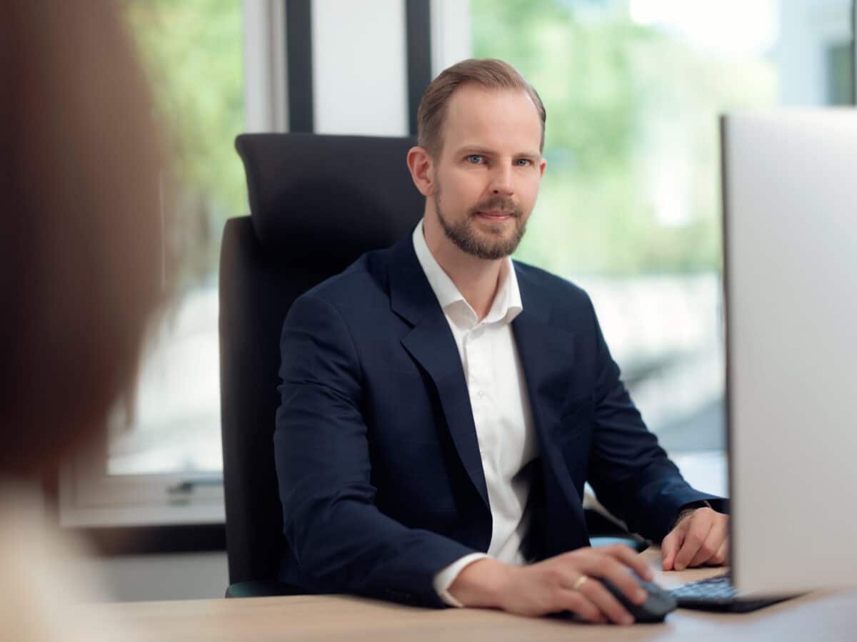 Advokat sitter ved pulten og ser inn i kamera